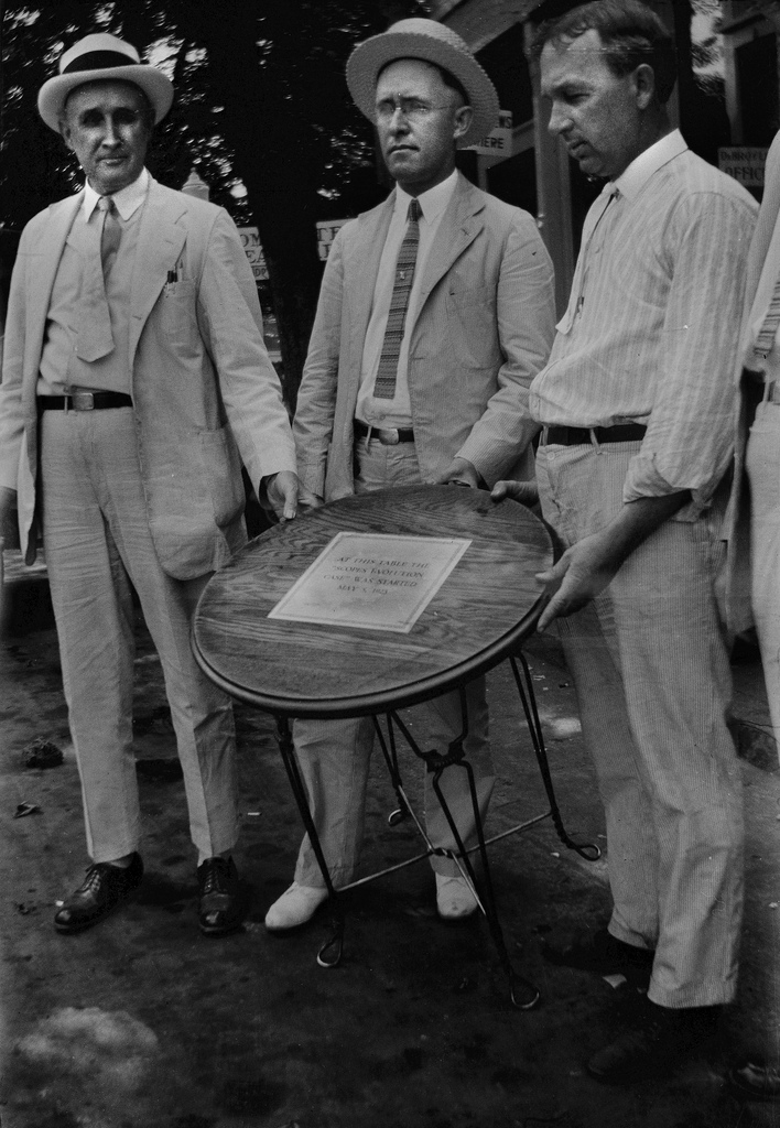 Fred E. Robinson (at right) owned the drugstore where local business leaders persuaded schoolteacher John Thomas Scopes to consent to be charged with violating state law by teaching about evolution. The sign on the tabletop says: â€œAT THIS TABLE THE SCOPES EVOLUTION CASE WAS STARTED MAY 5, 1925.â€